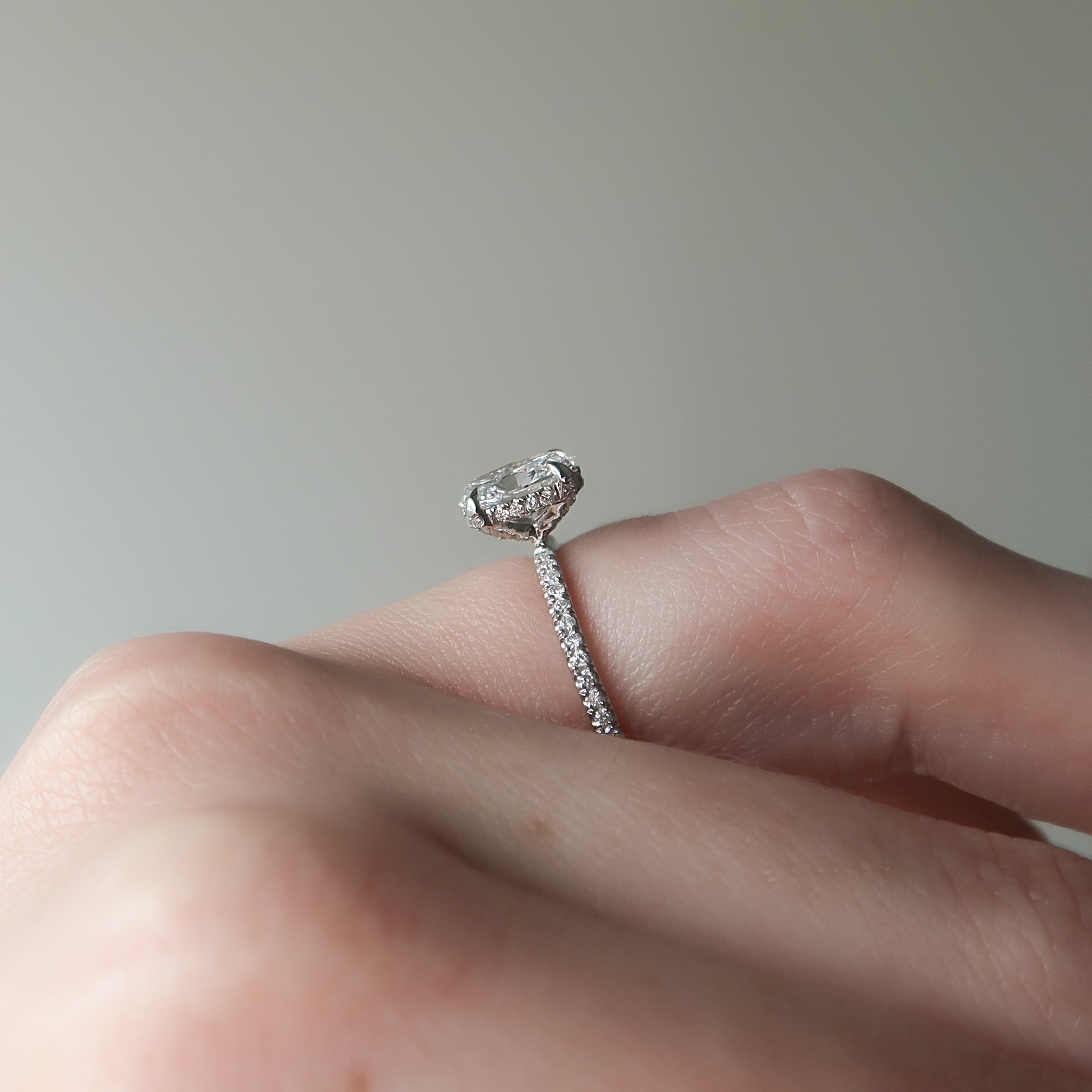 Oval cut CVD diamond engagement ring featuring hidden halo and pave band in platinum