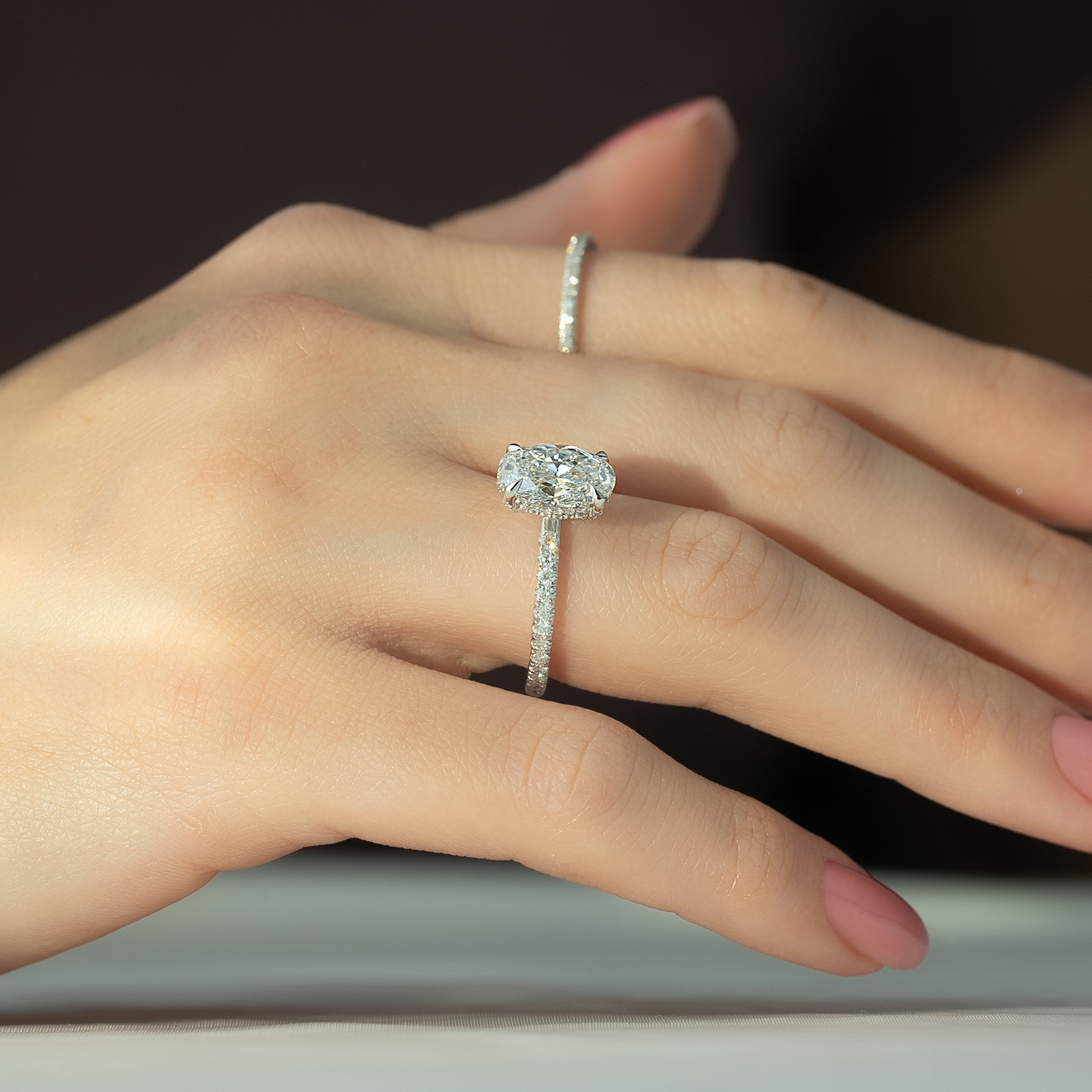 Oval cut CVD diamond engagement ring featuring hidden halo and pave band in platinum