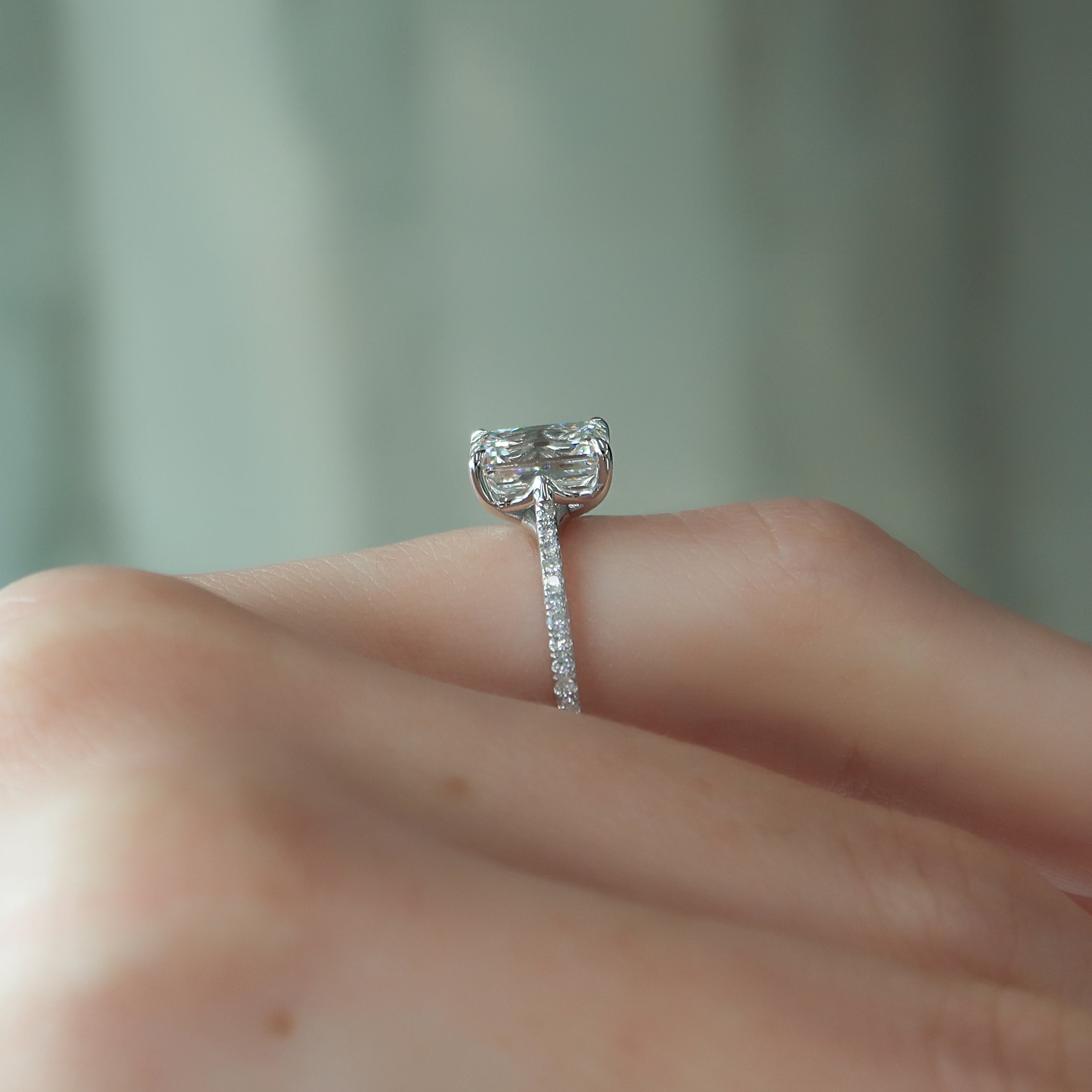 Emerald cut moissanite engagement ring with pave diamond band in white gold setting