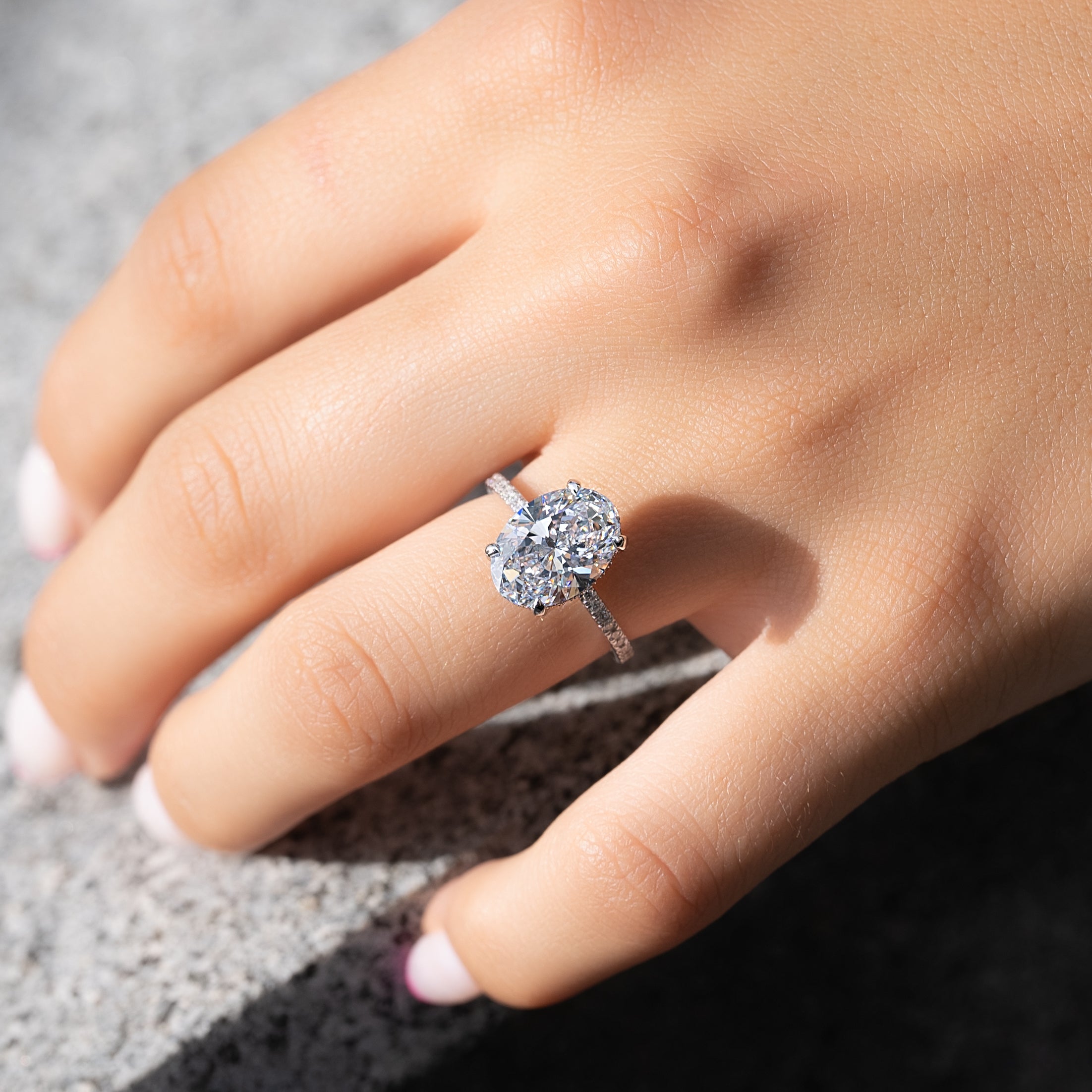 Oval cut CVD diamond engagement ring featuring hidden halo and pave band in platinum