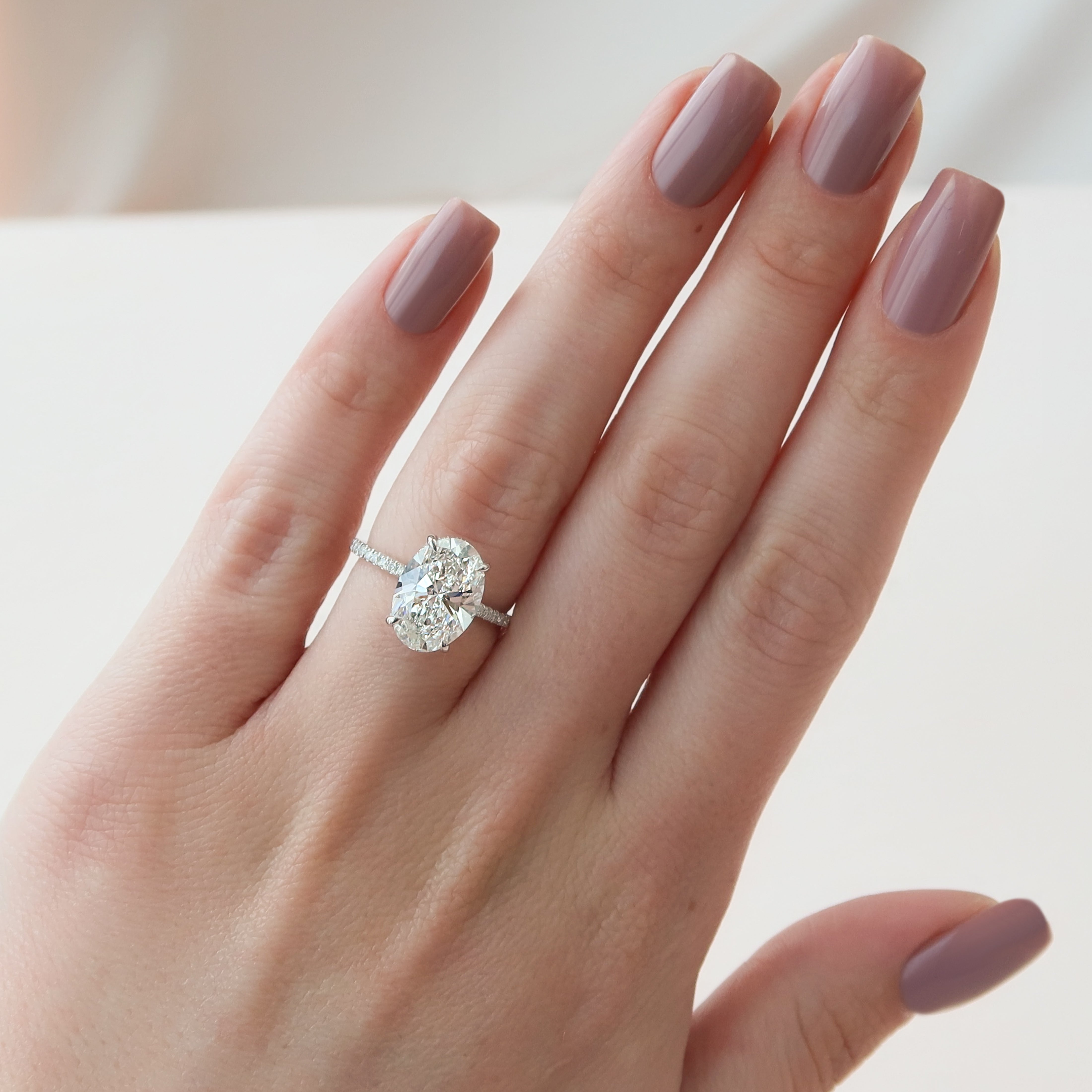 Oval cut CVD diamond engagement ring featuring hidden halo and pave band in platinum
